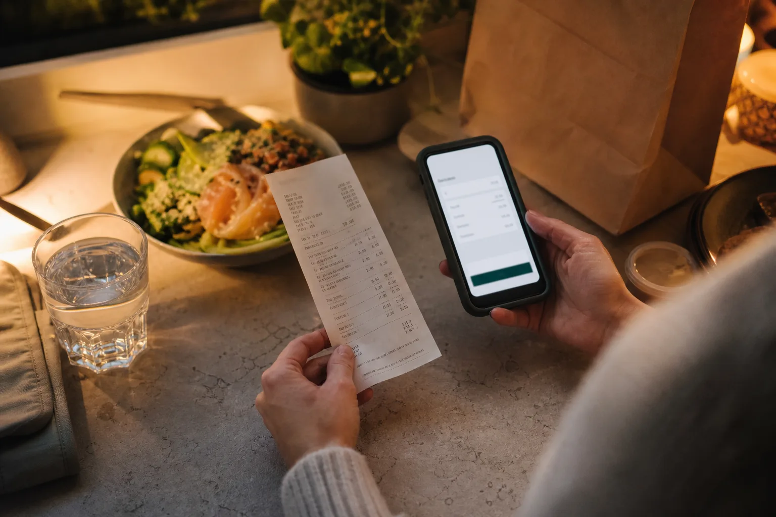 Kvitto med flera kostnadsrader bredvid en mobiltelefon med en matbeställning i kassavyn