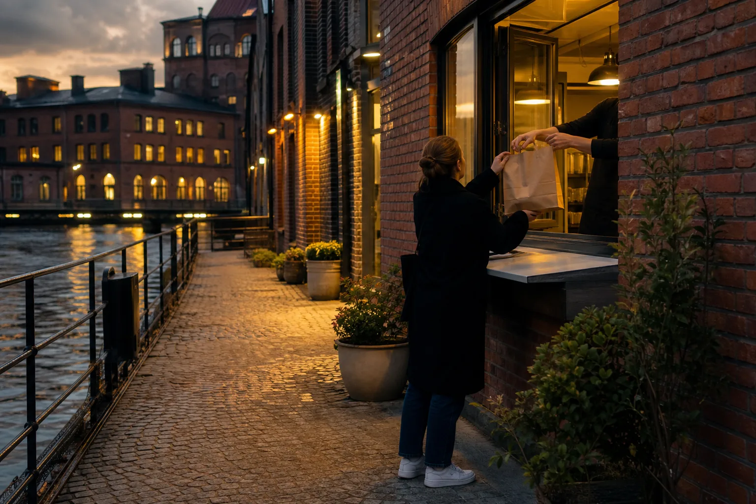 Illustrativ kvällsbild av tegelfasader vid ett vatten i en svensk industristad, med en person som hämtar en matkasse