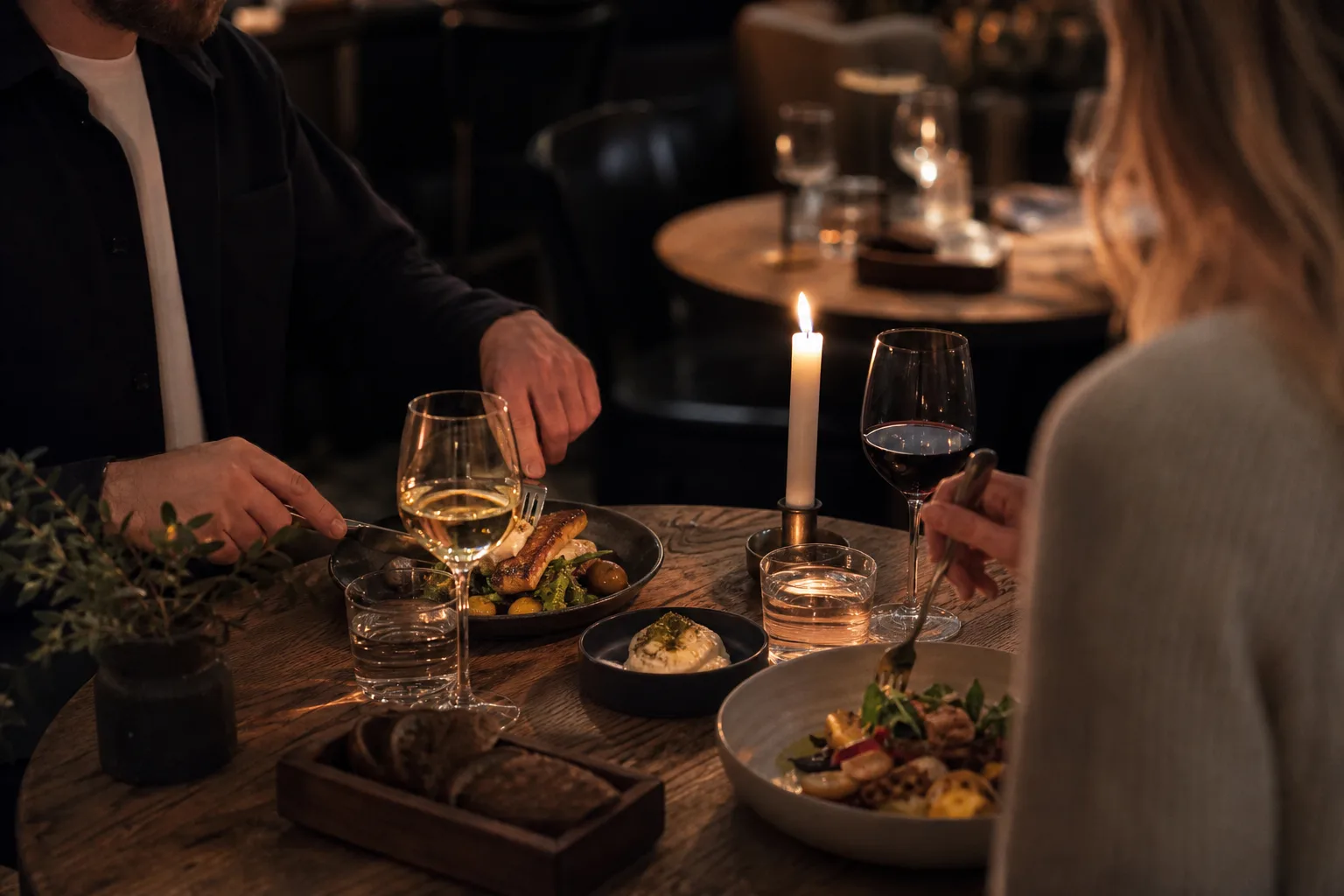 Ett par sitter vid ett levande ljus-dukat restaurangbord en avslappnad kväll i en sydsvensk stad